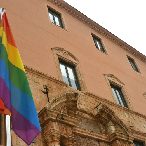 Foto de la bandera LGBTI+ onejant davant la façana de l'Ajuntament