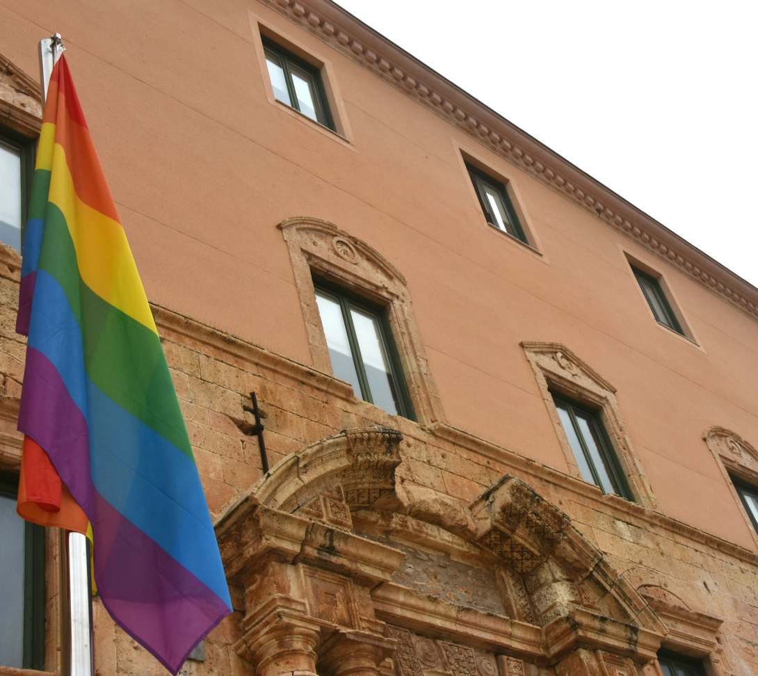 Foto de la bandera LGBTI+ onejant davant la façana de l'Ajuntament